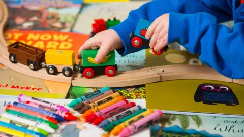 Dominic Lipinski/PA A child playing with a toy train set