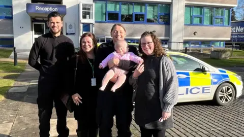 A group of smiling people outside a police station