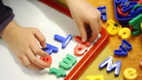 Child playing with brightly-coloured magnetic letters