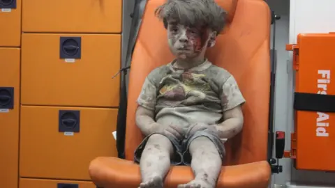 MAHMOUD RSLAN/AFP/Getty Images Photo showing Syrian boy Omran Daqneesh after his home was destroyed by an air strike in Qaterji, Aleppo, on 17 August 2016