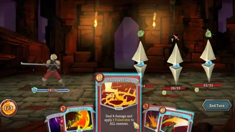 Megacrit A screenshot from Slay the Spire showing the player character clad in armour and wielding a long, thin sword in front of a medieval castle with its drawbridge down. Three identical enemies - a blue orb with two pyramidal shapes attached are opposite, In the lower screen a card reading "Thunderclap: Deal 4 damage and apply 1 Vulnerable to All enemies" is visible