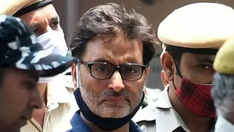 Yasin Malik, chairman of Jammu Kashmir Liberation Front (JKLF), a separatist party, is escorted by Indian police officers at a court premises in New Delhi, India, May 25, 2022.