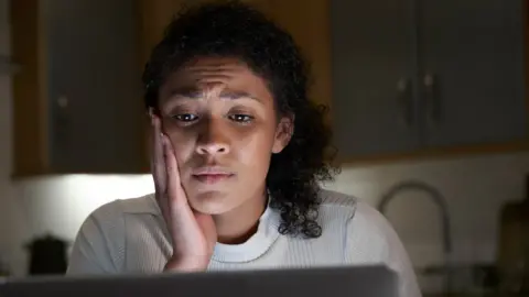 Getty Images A woman looking at abusive messages on her computer