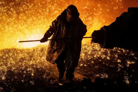 Geoff Caddick / AFP Cast House operator Martin Rees changes the nozzle on a clay gun in Blast Furnace number four at the Tata Steel Port Talbot integrated iron and steel works in south Wales, 15 August, 2023.
