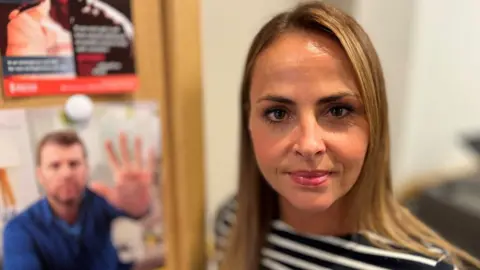 BBC Sophie Williams inside her Nationwide branch stood in front of two anti fraud posters