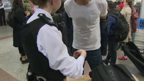 BBC A man being searched by a policewoman