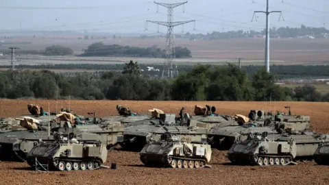 Reuters Israeli soldiers stand on armoured personnel carriers near the border with Gaza (13 November 2019)