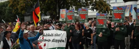 Getty Images Protesters in Chemnitz on 27 August hold signs reading: 'Stop the Asylum Flood!'