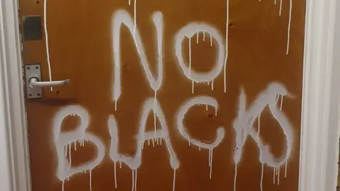 Jackson Yamba "No Blacks" graffiti daubed on door