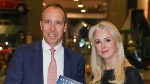 Andrew Parsons/Parsons Media Matt Hancock and Isabel Oakeshott standing together, both smiling at the camera and holding a copy of Mr Hancock's book between them