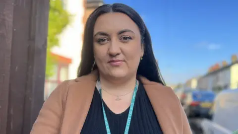 Emma Baugh/BBC News Housing officer in a Peterborough street