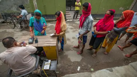 AFP People stand in queue amidst the process of receiving free ration. Government Ration shops distributed 5Kg free food grain under the Pradhan Mantri Garib Anna Yojana (PMGAY) during the Covid-19 crisis