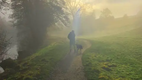 Mist around a dog walker in the village of Curbar in Derbyshire