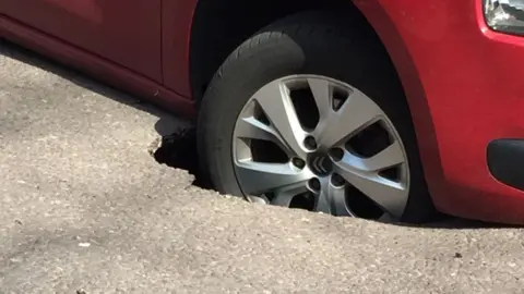 Car wheel stuck in "sinkhole"