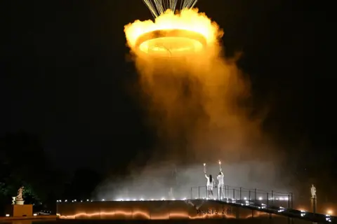 Mohd Rasfan/AFP The cauldron, with the Olympic flame lit, lifts off while attached to a balloon as the torchbearers French former sprinter Marie-Jose Perec and French judoka Teddy Riner stand in front during the opening ceremony of the Paris 2024 Olympic Games at the Jardin des Tuileries