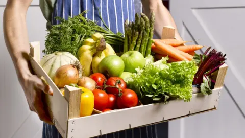 Getty Images Man holding box of fruit and veg