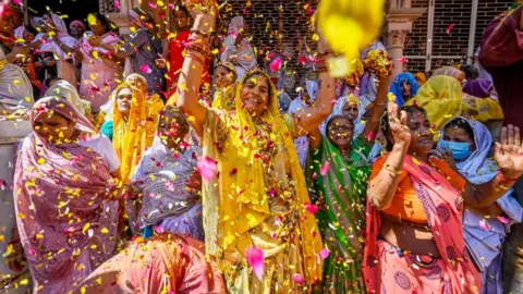 Getty Images Widows throw petals and Flowers while participating in the Holi festival at Gopinath Temple on March 6, 2023 in Vrindavan, India.