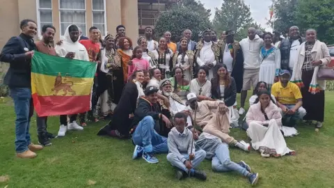 Ras Benji A group photo of people holding up the Rastafari flag