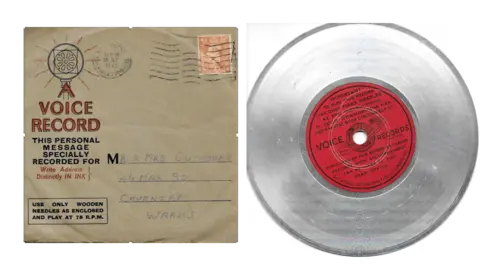 Pauline Tasker A square brown envelope has printed in red "A voice record. This personal message specially recorded for: Write address distincly in Ink. It has the Coventry address of Mr and Mrs Cuthbert, 46 Max Road, Coventry, Warks. Next to this is an image of an aluminium disc with a red label in the centre. 