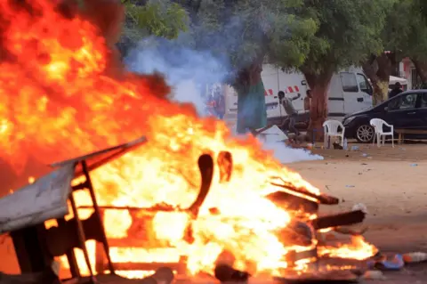 Zohra Bensemra/Reuters A man throws stones near burning objects during clashes between security forces and supporters of Senegalese opposition leader Ousmane Sonko in Dakar, Senegal - Monday 29 May 2023