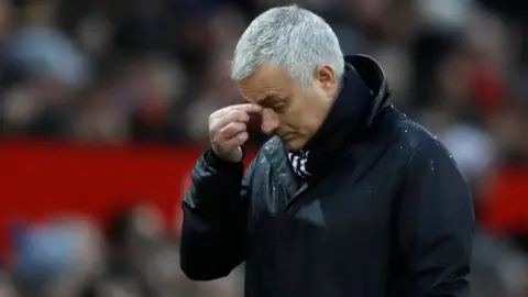 Reuters Mourinho pinches the bridge of his nose while standing on the field in this shallow depth of field shot from a football stadium