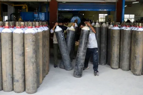 Getty Images Workers arrange medical oxygen cylinders to transport to hospitals for the Covid-19 coronavirus treatment in a facility on the outskirts of Hyderabad on April 23, 2021.