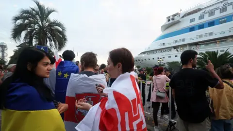 Ukrinform/NurPhoto via Getty Images Demonstrators protest against the arrival of the Astoria Grande cruise ship, with some 800 mostly Russian passengers on board, Batumi, Georgia.