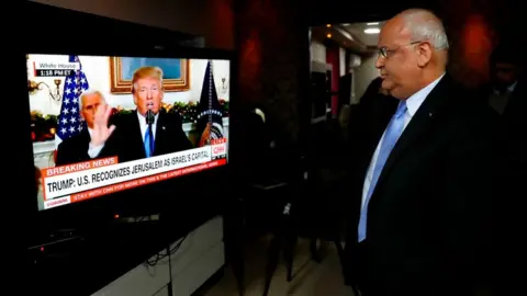 THOMAS COEX/AFP via Getty Images Saeb Erekat staring at Donald Trump on a screen