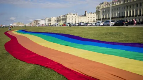 Getty Images A large rainbow Pride banner is spread out ahead of the annual Brighton Pride parade