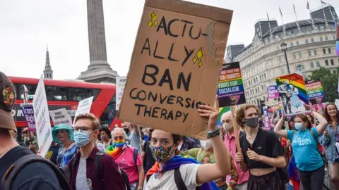 Getty Images A demonstrator holds a placard that says Actually Ban Conversion Therapy in Trafalgar Square during the Reclaim Pride protest.