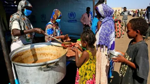 Getty Images Ethiopian refugees who have fled the Tigray conflict, receive food at a transit centre in Sudan's border town of Hamdayit on November 27, 2020.