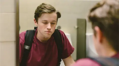 Getty Images Young adolescent boy looking in the mirror