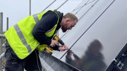 An installer working on an array of solar panels