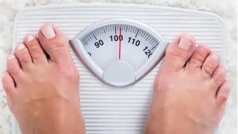 Getty Images Woman standing on weighing scales