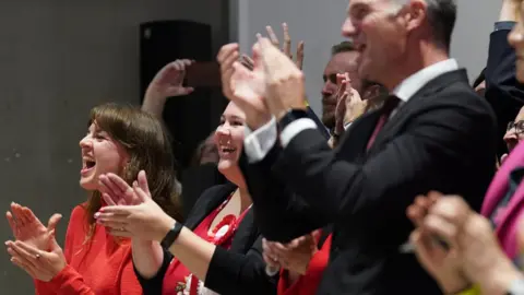 PA Media Campaigners clapping and celebrating after Labour win in Mid Bedfordshire