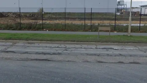 Google Tarmac road in industrial area, showing long ruts in the surface