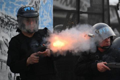 Riot police officer fires his gun