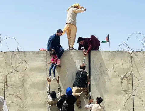 Getty Images Thousands of Afghans rush to the Hamid Karzai International Airport as they try to flee the Afghan capital of Kabul, Afghanistan, on 16 August 2021