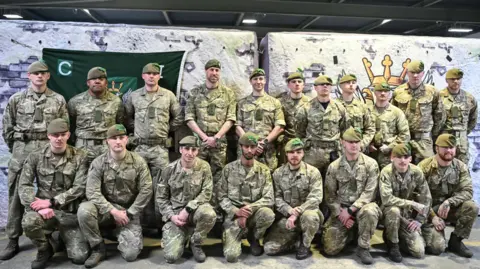 JUSTIN TALLIS/Pool via REUTERS Soldiers stood together in a group photo. They are all in camouflage gear and Prince William is stood among them on the back row