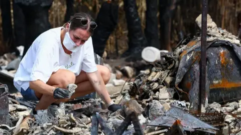 Reuters Julie inspects the debris of her parents' home after it was destroyed by a wildfire in Le Porge