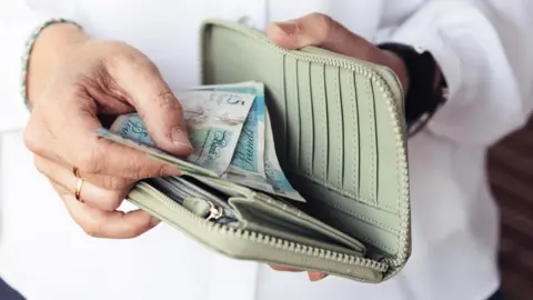 Getty Images Money being put in a purse