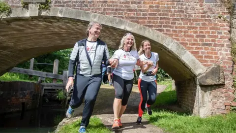 Heather running under bridge with family