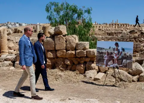 Getty Images Prince William, Duke of Cambridge and Crown Prince Hussein of Jordan walk past an enlarged photo of Catherine, Duchess of Cambridge in her youth with her father on a family holiday