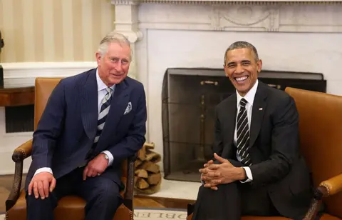 Getty Images Charles and Obama smiling for the camera as they sit in chairs at the White House