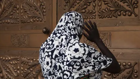 FLORIAN PLAUCHEUR Woman stands outside mosque entrance