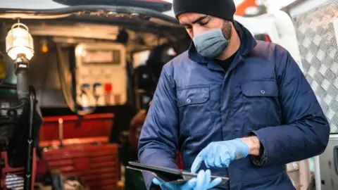 Getty Images Plumber wearing mask and gloves