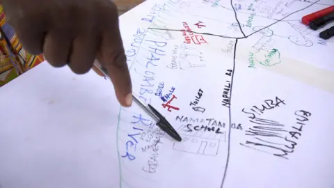 Malawi Red Cross volunteers point on a hand-drawn map with a pen