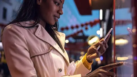 Getty Images Woman on smartphone and interactive touchscreen