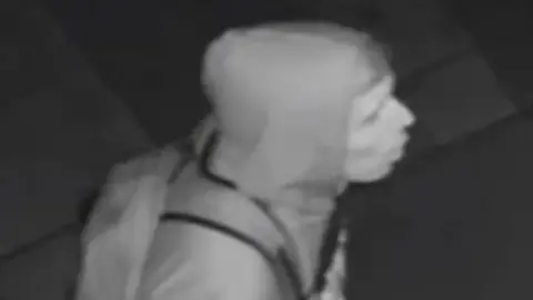 Met Police Black and white image showing a side profile of the suspect wearing a hoodie and backpack