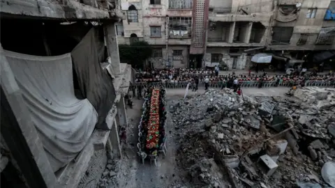 European Photopress Agency People wait for Iftar, evening meal at the end of daily Ramadan fast at sunset, next to rubble and destroyed houses, which were damaged after air strikes, in Douma, Syria, 17 June 2017.